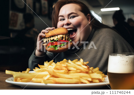 Fat girl eating hamburger in fast food restaurant.  111740244