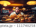 Fat man eating hamburger in fast food restaurant.  111740258