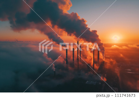 The setting sun casts a vivid backdrop behind towering smokestacks, as thick smoke billows into the sky, highlighting the stark contrast between natural beauty and industrial pollution. 111741673