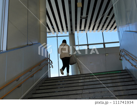 駅の階段を登る一人の若い女性の姿 111741934