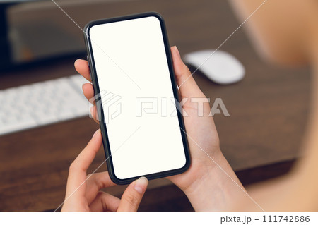 Woman hand holding smartphone mockup of blank screen for graphic display montage. 111742886