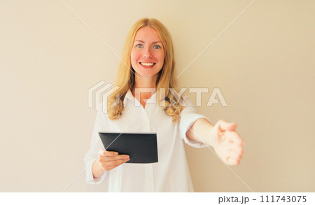 Happy smiling woman employer greets applicant holds digital tablet computer in office Happy smiling woman employer greets applicant holds digital tablet computer in office 111743075