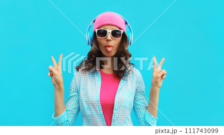Portrait of stylish modern happy young woman listening to music with headphones in colorful clothes 111743099