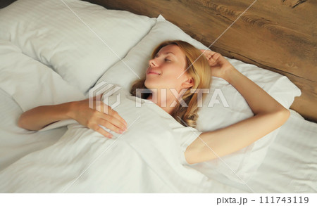 Young woman sleeping lying in bed on white soft comfortable pillow in bedroom at home 111743119