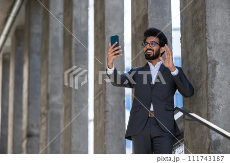 Smiling young businessman having a video call and looking contented 111743187
