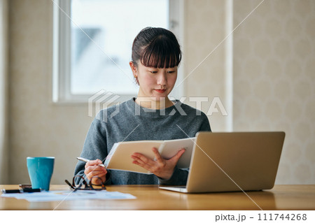 ノートを手に持ち調べごとをする若い女性 111744268