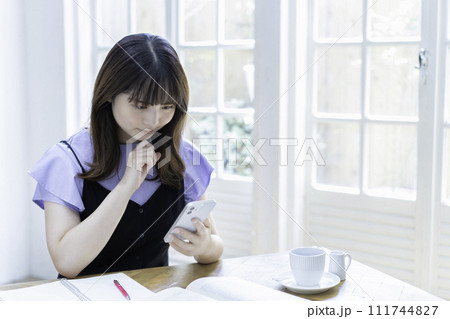 勉強中にスマホを使う若い女性 勉強中にスマホを使う若い女性 111744827