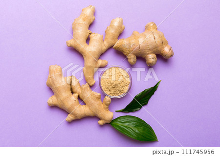 Finely dry Ginger powder in bowl with green leaves isolated on colored background. top view flat lay 111745956