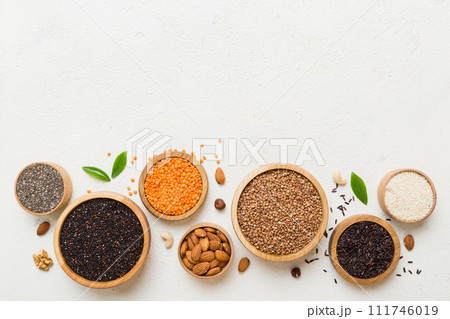 Various superfoods in smal bowl on colored background. Superfood as rice, chia, quinoa, lentils, nuts, sesame seeds, almonds. top view copy space 111746019