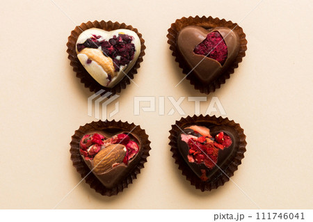 chocolate sweets in the form of a heart with fruits and nuts on a colored background. top view with space for text, holiday concept 111746041