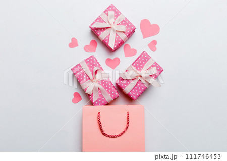 Gift boxes pop out from paper bag top view on colored background. bag packing handmade boxes fall out Concept of holidays, shopping, sale, discounts. Top view, flat lay 111746453