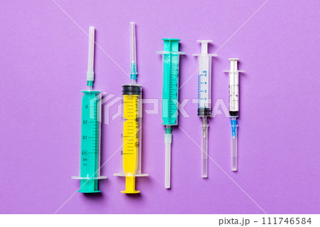 Top view of medical syringes with needles at purple background with copy space. Injection treatment concept Top view of medical syringes with needles at purple background with copy space. Injection treatment concept 111746584