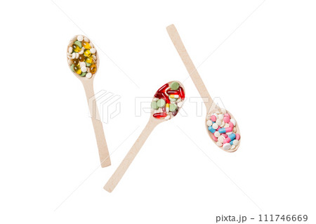 Vitamin capsules in a wooden spoon on a colored background. Pills served as a healthy meal. Drugs, pharmacy, medicine or medical healthycare concept 111746669