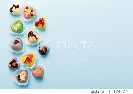 chocolate sweets in the form of a heart with fruits and nuts on a colored background. top view with space for text, holiday concept chocolate sweets in the form of a heart with fruits and nuts on a colored background. top view with space for text, holiday concept 111746770