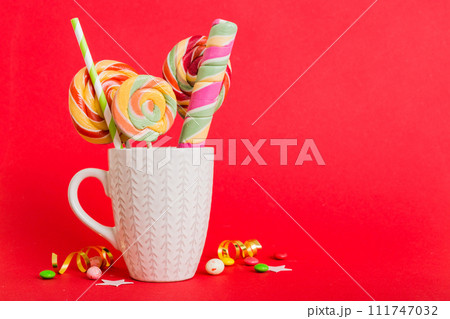 Colorful candies in cup on table on light background background. Large swirled lollipops. Creative concept of a jar full of delicious sweets from the candy store 111747032
