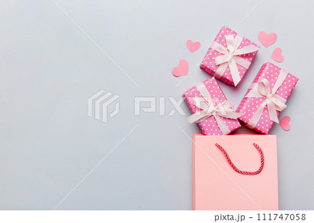 Gift boxes pop out from paper bag top view on colored background. bag packing handmade boxes fall out Concept of holidays, shopping, sale, discounts. Top view, flat lay Gift boxes pop out from paper bag top view on colored background. bag packing handmade boxes fall out Concept of holidays, shopping, sale, discounts. Top view, flat lay 111747058