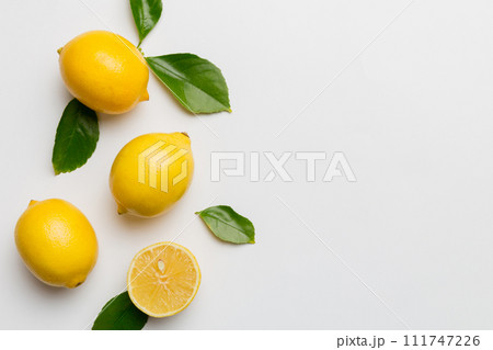Many fresh ripe lemons with green leaves on colored background, top view, space for text Many fresh ripe lemons with green leaves on colored background, top view, space for text 111747226