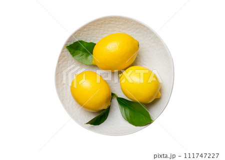 Fresh cutted lemon and whole lemons over round plate isolated on white background. Food and drink ingredients preparing. healthy eating theme top view with copy space Fresh cutted lemon and whole lemons over round plate isolated on white background. Food and drink ingredients preparing. healthy eating theme top view with copy space 111747227