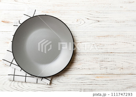 Top view on colored background empty round gray plate on tablecloth for food. Empty dish on napkin with space for your design Top view on colored background empty round gray plate on tablecloth for food. Empty dish on napkin with space for your design 111747293