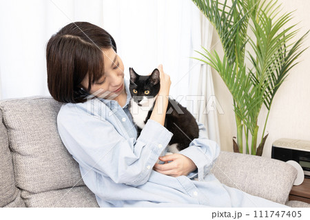 ソファーに座って仔猫を抱く女性 111747405