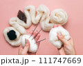 woman hand holding skein of wool and needle felting kit. felted woolen wool on pink background, handicraft from above. flat lay 111747669