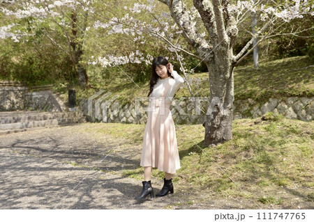 サクラ咲く公園でポーズをとる若くスリムな女性 サクラ咲く公園でポーズをとる若くスリムな女性 111747765