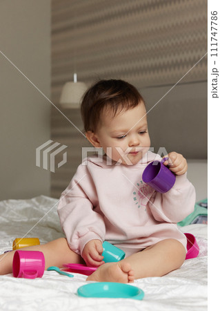 happy cute little child girl playing and pretending drinking tea from toy cups on bed happy cute little child girl playing and pretending drinking tea from toy cups on bed 111747786