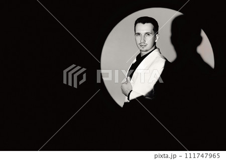 elegant man in white suit tuxedo in the circle of light, copy space. black and white elegant man in white suit tuxedo in the circle of light, copy space. black and white 111747965
