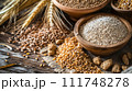 A rustic assortment of whole grains, wheat ears, and cereals displayed in wooden bowls on a textured wooden table. 111748278