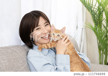 仔猫と頬を寄せて微笑む女性 111748899