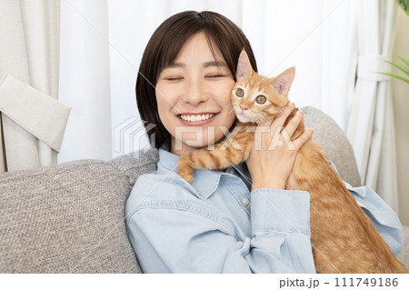 仔猫と頬を寄せて微笑む女性 111749186