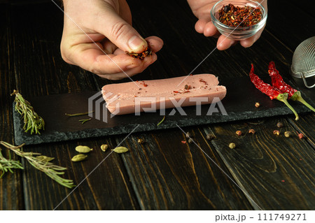 Cooking Munich milk sausage on the kitchen table. The chef hands add aromatic spices to the sausage on the kitchen table before baking in the oven. Serving diet food for breakfast. Cooking Munich milk sausage on the kitchen table. The chef hands add aromatic spices to the sausage on the kitchen table before baking in the oven. Serving diet food for breakfast. 111749271