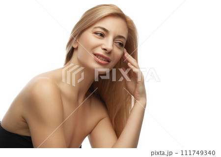 Portrait of beautiful, elegant woman with bare shoulders holds her hands near cheek against white studio background. Portrait of beautiful, elegant woman with bare shoulders holds her hands near cheek against white studio background. 111749340