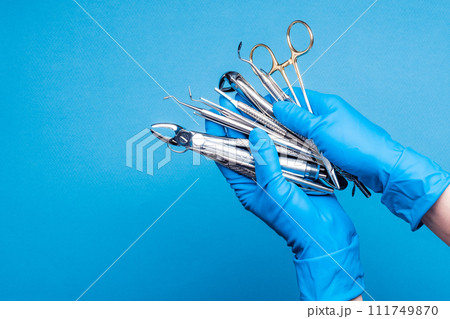 Hands in blue gloves holding dental equipment and metal instruments 111749870