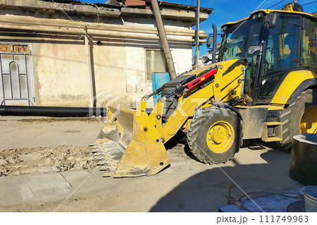 A yellow excavator stands at the site of planned repairs to underground communications, heating, and water supply systems during a lunch break A yellow excavator stands at the site of planned repairs to underground communications, heating, and water supply systems during a lunch break 111749963