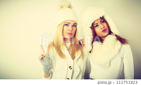 Two girls in warm winter clothing having fun. 111751823