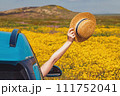 Summer road trip concept. Hat holding a straw hat from opened car window 111752041