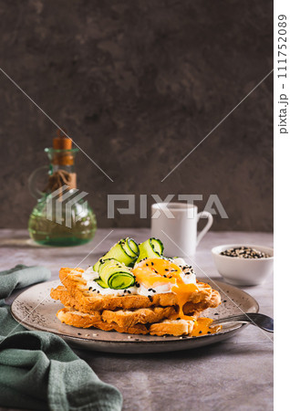 Toasts with cream cheese, cucumber, poached egg and sesame seeds on a plate vertical view 111752089