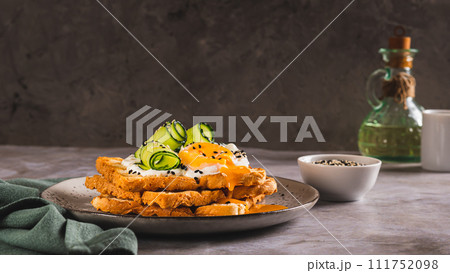 Toasts with cream cheese, cucumber, poached egg and sesame seeds on a plate web banner 111752098