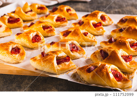 Homemade envelopes with cheese and pepperoni sausage on paper on a board Homemade envelopes with cheese and pepperoni sausage on paper on a board 111752099