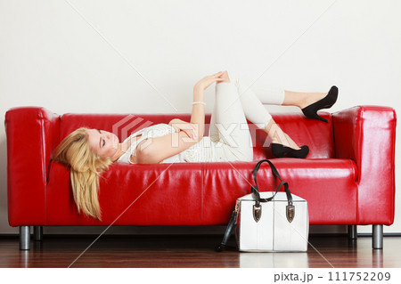 Woman lying on sofa presenting white bag 111752209