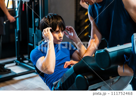 フィットネスジムでトレーナーの指導を受ける男性 111752468