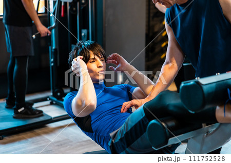 フィットネスジムでトレーナーの指導を受ける男性 フィットネスジムでトレーナーの指導を受ける男性 111752528
