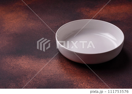 Empty ceramic round plate on dark textured concrete background Empty ceramic round plate on dark textured concrete background 111753576
