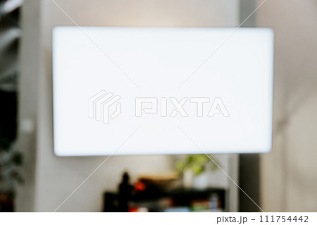 TV at wall in living room. Watching smart television indoors. White empty mockup screen, copy space. Movie stream service. Video on demand subscription platform. Manage appliances of smart home 111754442