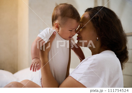 Loving affectionate young woman mother holding her newborn baby face to face, enjoying happy time of her maternity leave 111754524