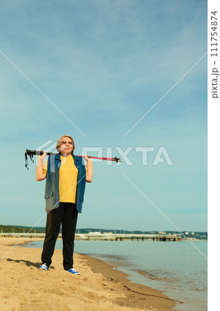 active woman senior nordic walking on a beach active woman senior nordic walking on a beach 111754874