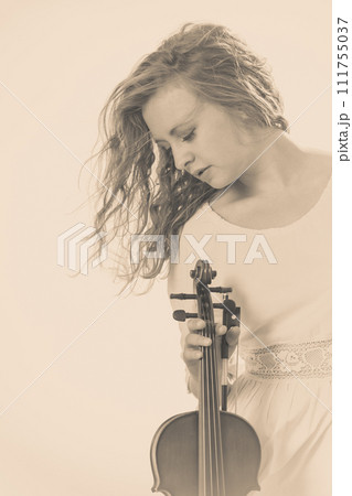 Woman on beach near sea holding violin Woman on beach near sea holding violin 111755037