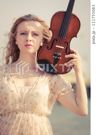 Woman on beach near sea holding violin 111755063
