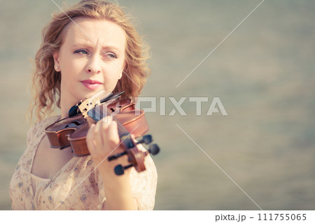 Woman playing violin on violin near beach 111755065